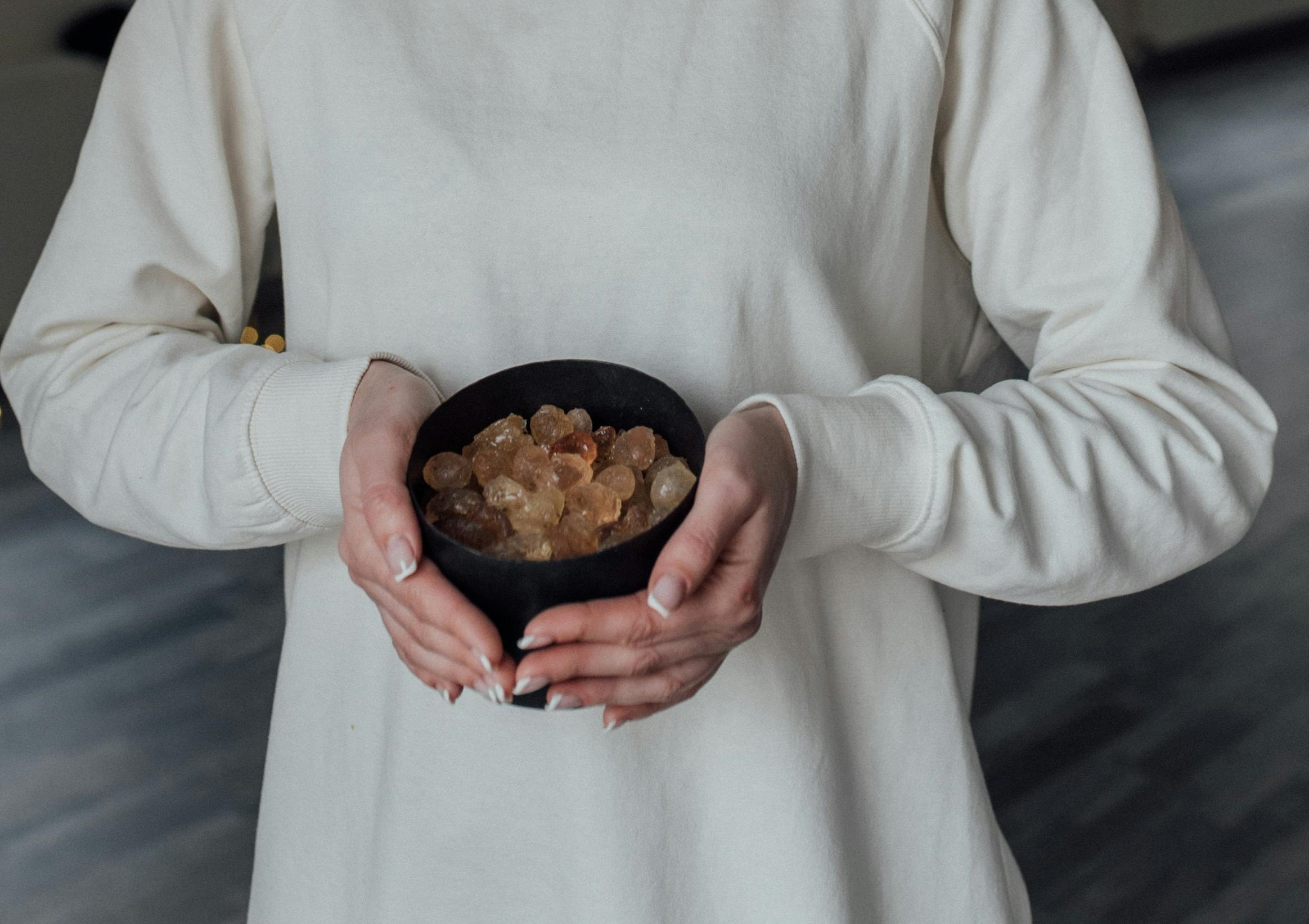 Person holding a small bowl of golden Frankincense resin.
