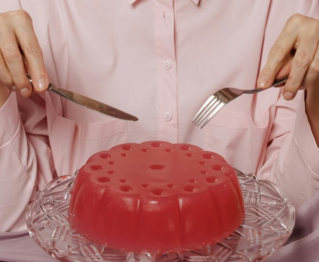 A person in pink about to eat a red gelatin mold.
